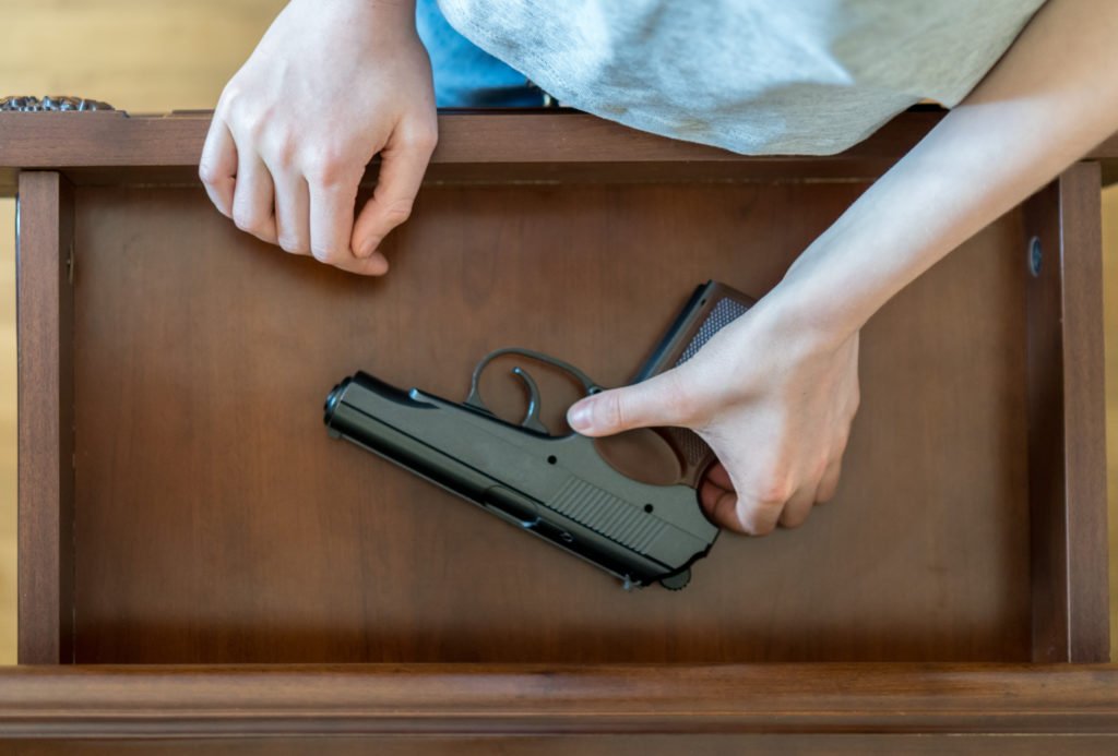 Persona sacando una pistola de un cajón