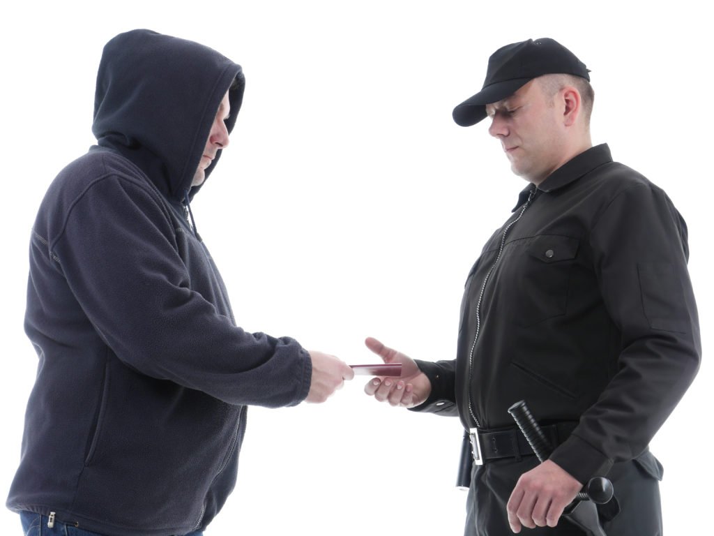 Hombre dando a otra persona su tarjeta de identificación para usar en violación del Código de Vehículos 13004 VC