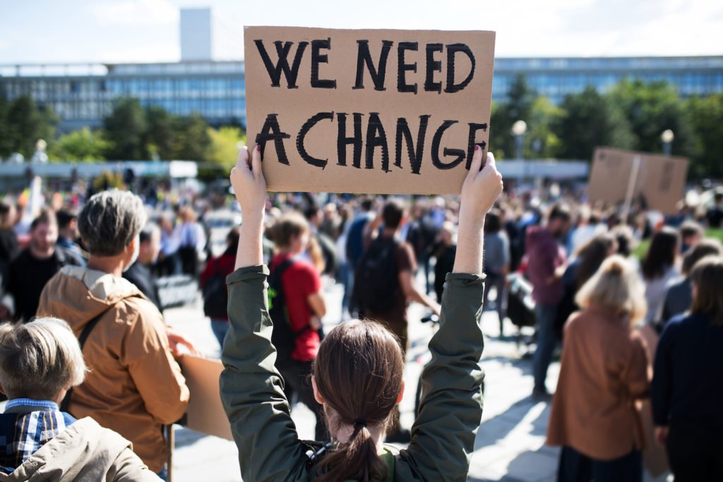 Manifestante político sosteniendo un letrero que dice 'Necesitamos un cambio', lo que no sería una base legal para despedir al manifestante en California