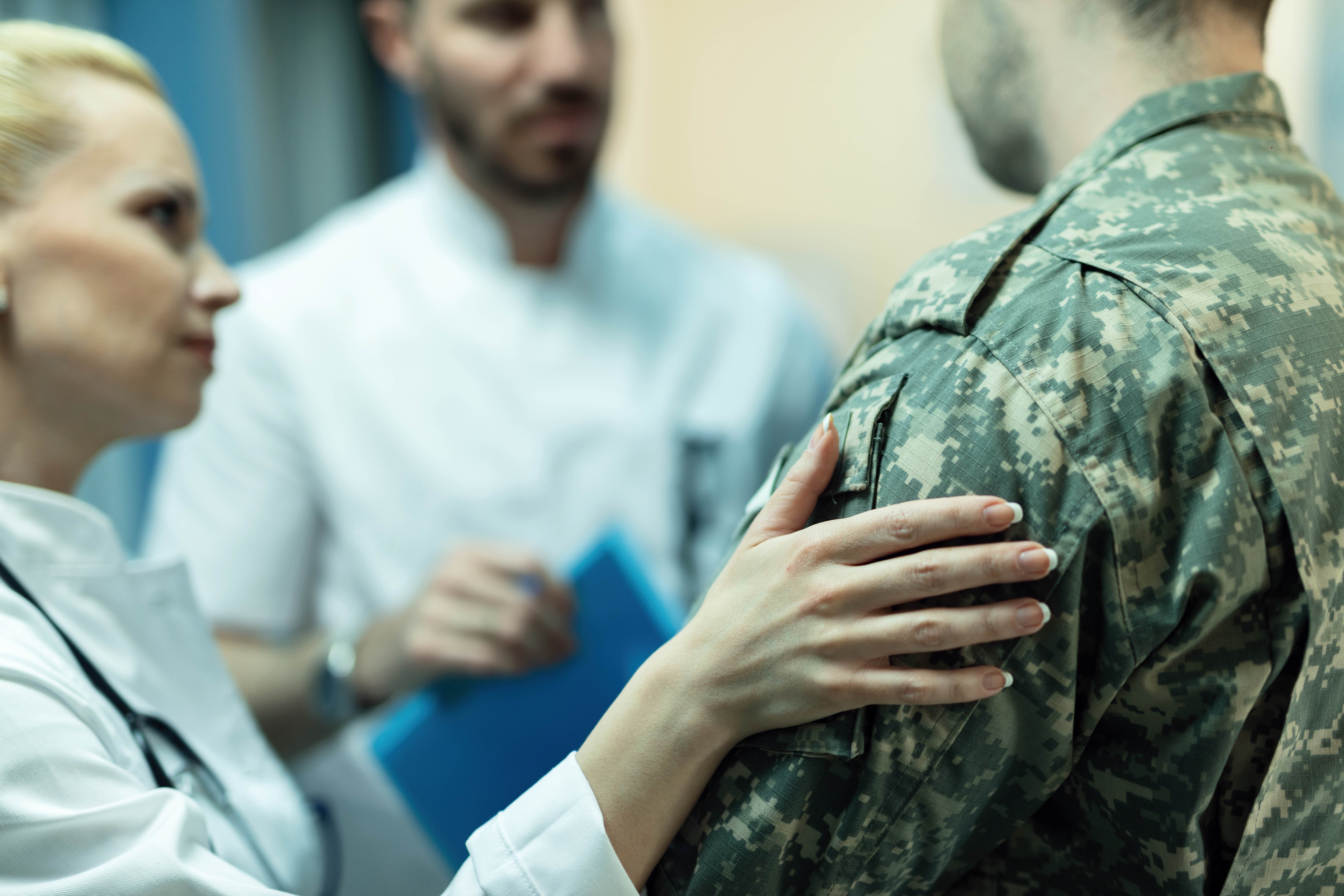 Man in fatigues receiving support by doctors