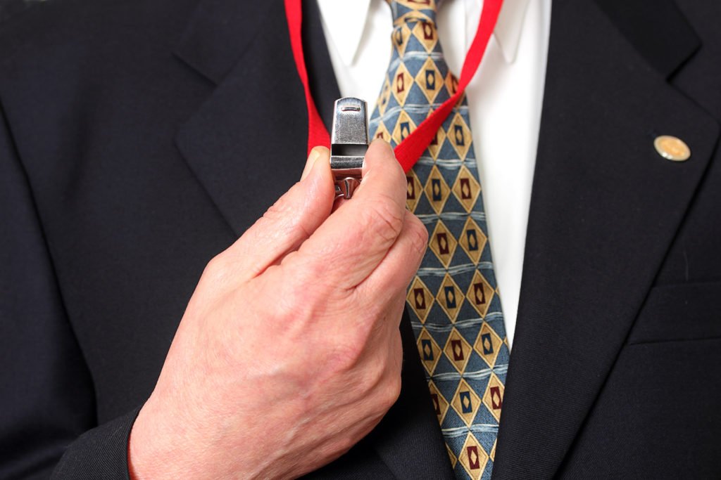 Closeup of man's hand holding up a whistle