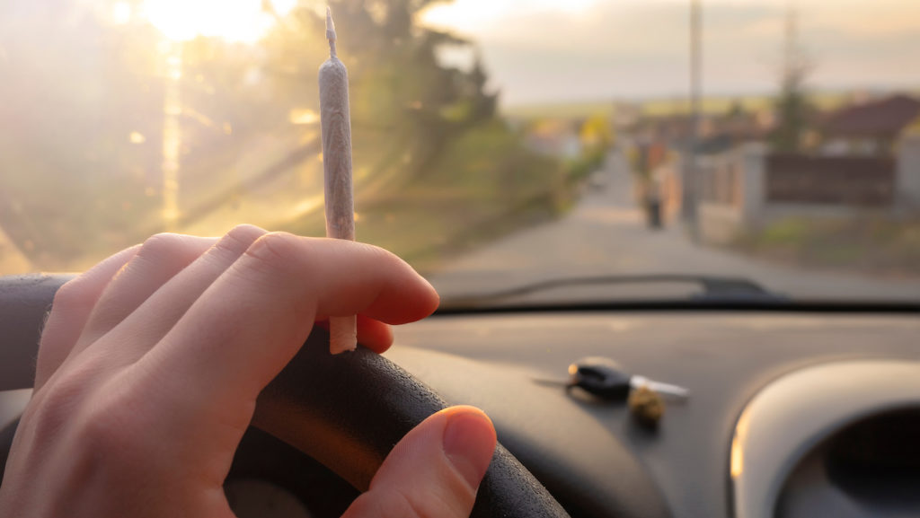 Closeup de la mano en el volante sosteniendo una articulación