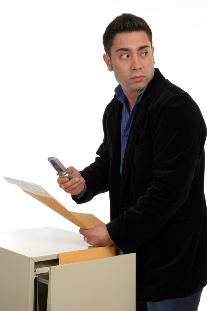 Hombre sacando archivos y fotografiándolos mientras mira por encima de su hombro