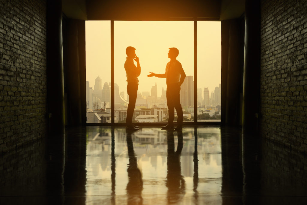 Dos personas hablando de negocios en un pasillo oscuro