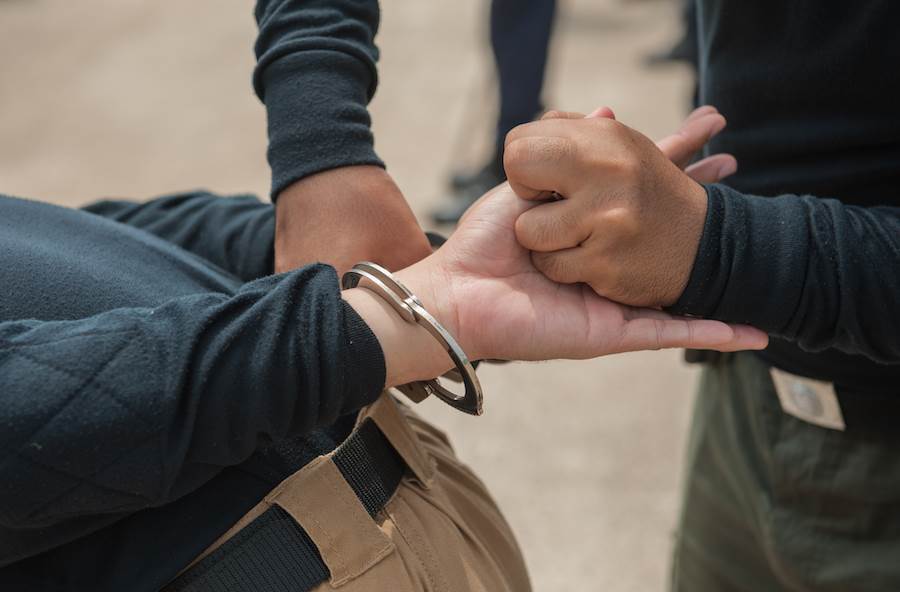 Un oficial de paisano esposando a un detenido después de violar el CRS 18-8-103