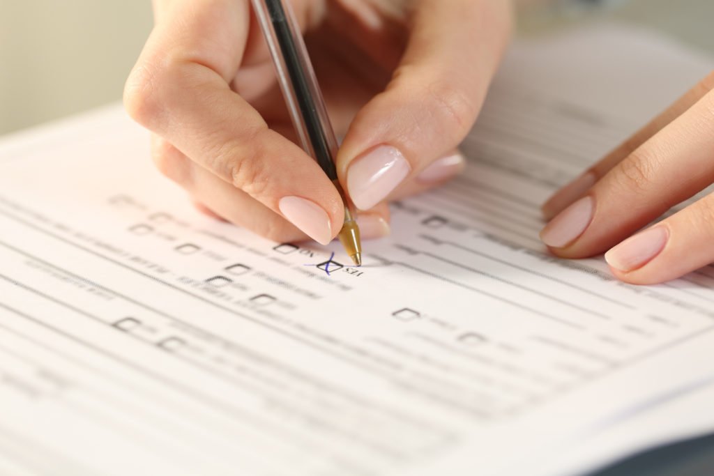 Close-up of a female hand with a pen filling out a job application