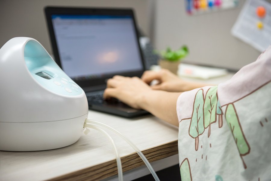 Pumping machine on work desk while Mom is typing on computer