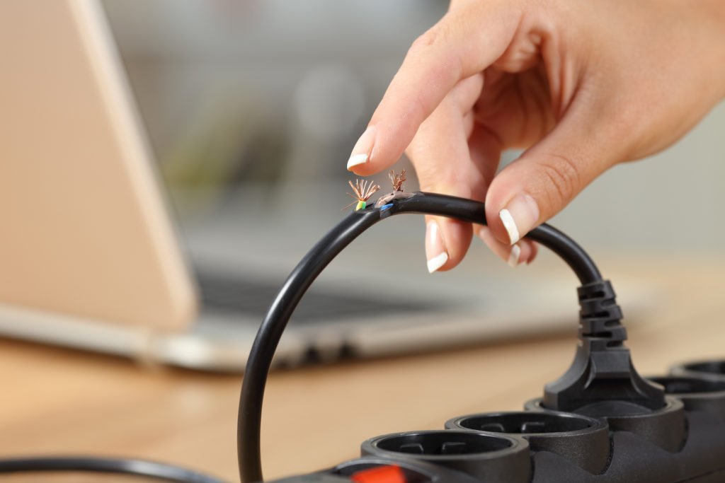 Close up of hand handling electric cord with exposed wire