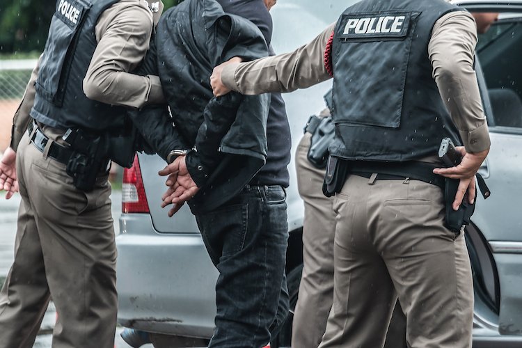 Fugitive being arrested by two police officers