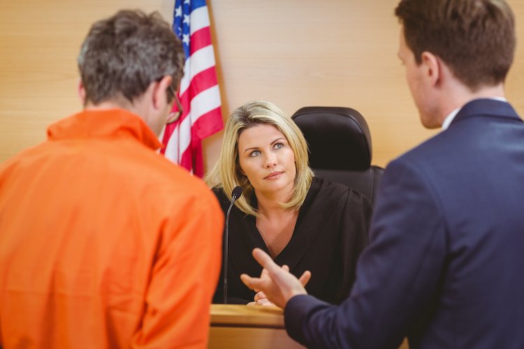 Abogado y acusado en audiencia de fianza hablando con el juez