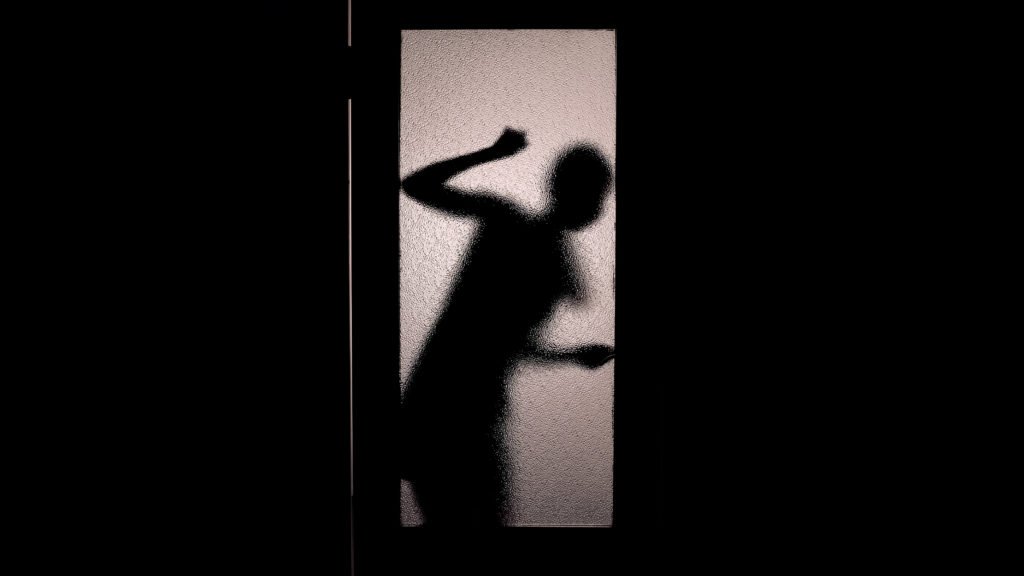 Woman silhouette behind door she is trapped behind due to false imprisonment