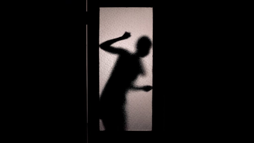 Silueta de una mujer detrás de una puerta de la que está atrapada debido al encarcelamiento falso