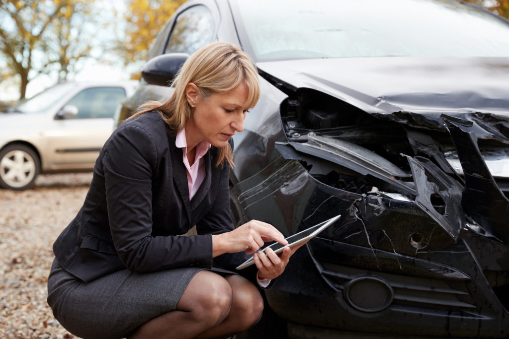 Un ajustador de seguros con Ipad inspeccionando un vehículo dañado - la doctrina de Made Whole coloca límites en la subrogación de la compañía de seguros