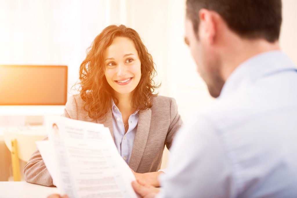 Male employer looking at a resume of a female job applicant across the table during a job interview