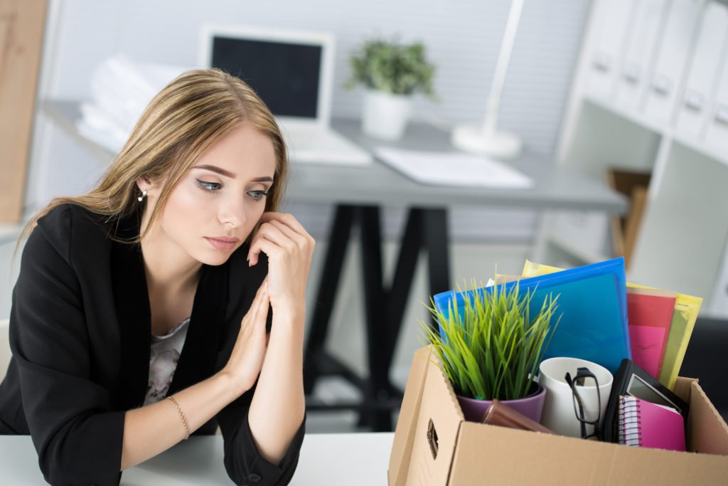 Empleado despedido junto a una caja de pertenencias en su antiguo escritorio de trabajo