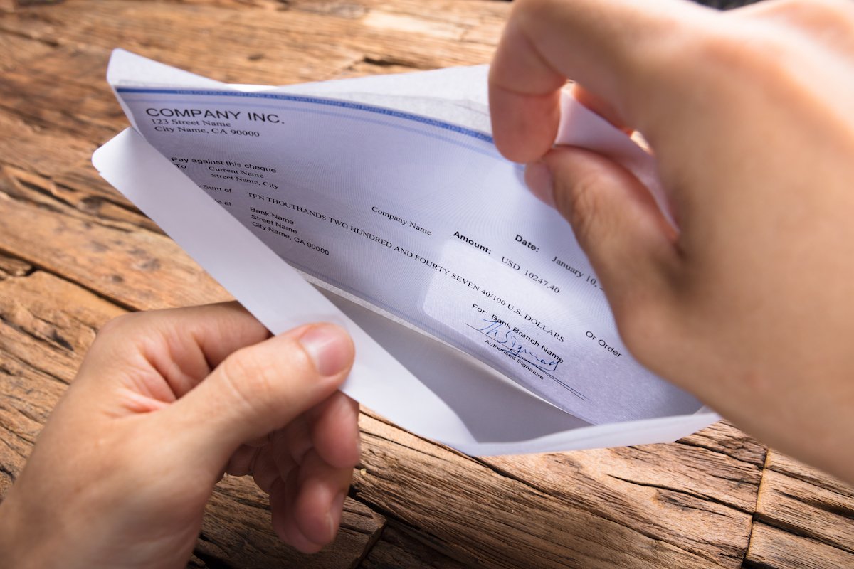 Closeup of worker opening paycheck envelope