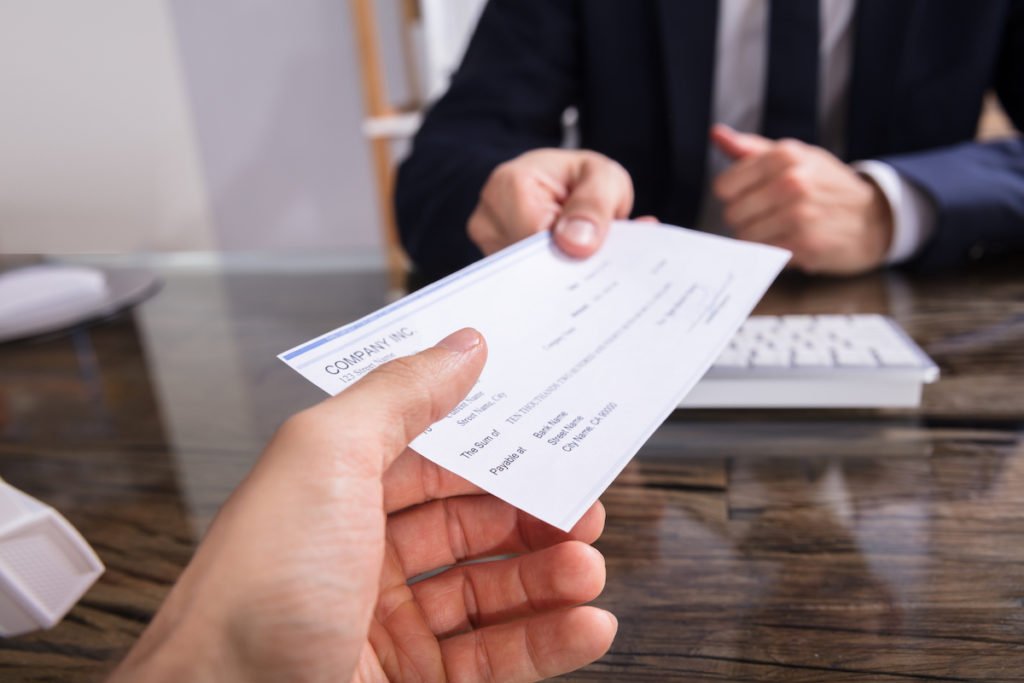 Boss handing paycheck to worker