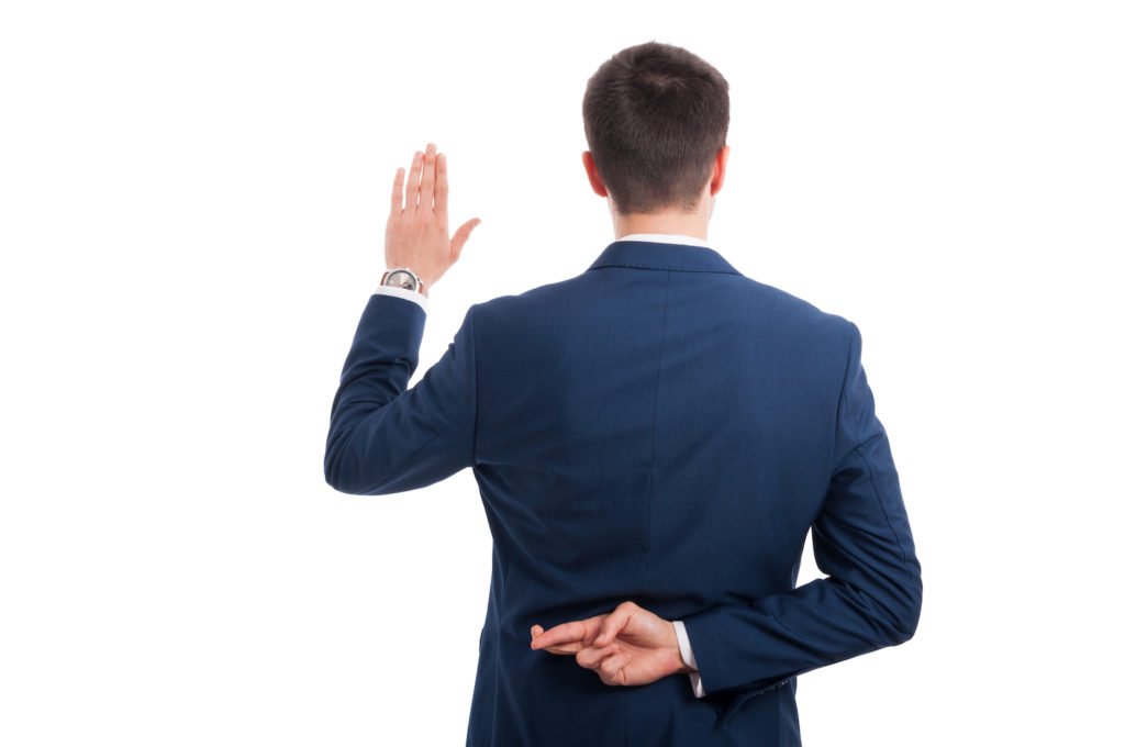 Hombre levantando la mano para dar juramento con la otra mano detrás de la espalda cruzando los dedos