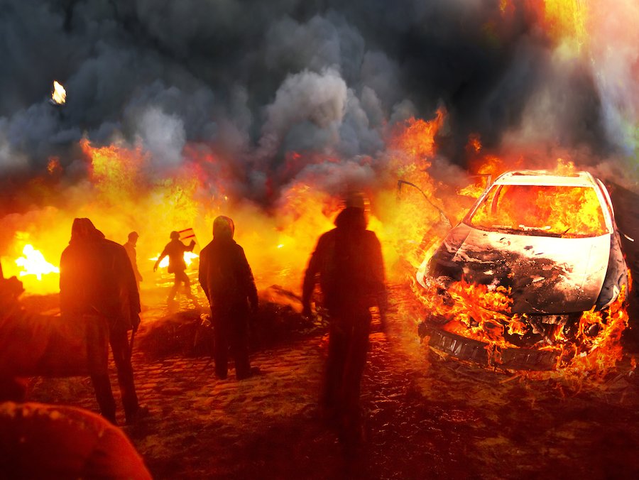 Five rioters near police car they set fire to as an example of a rioting offense per Colorado CRS 18-9-104