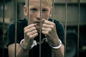 Youth behind bars in handcuffs