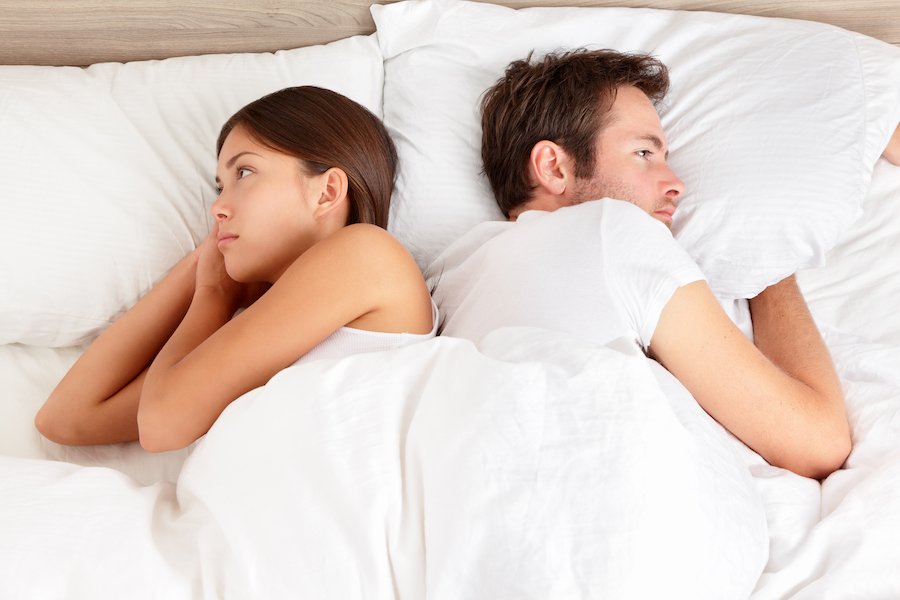 Hombre y mujer en la cama de espaldas el uno al otro