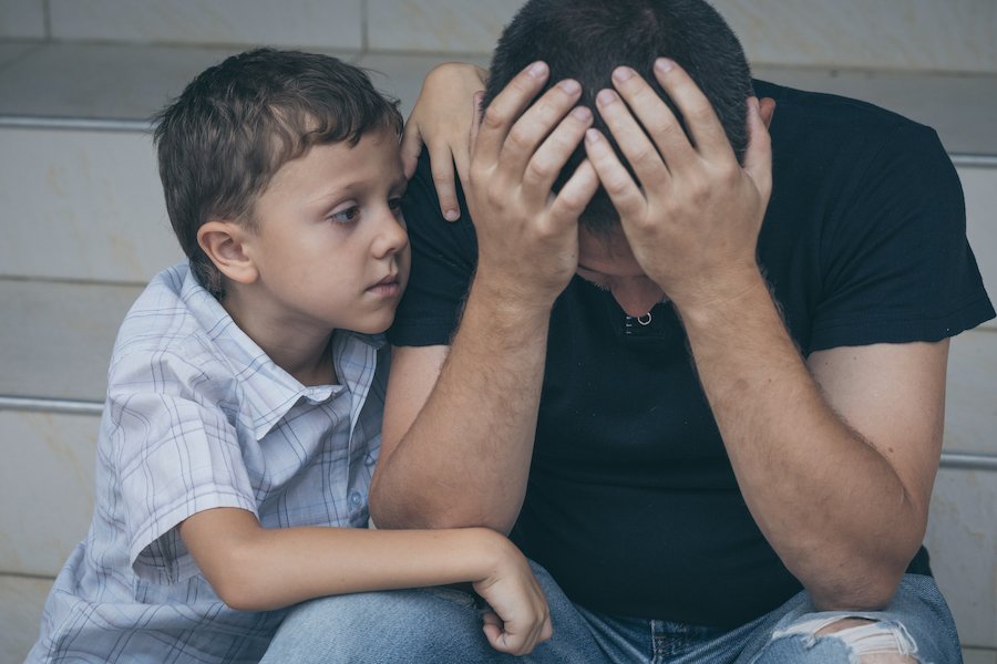 Padre triste mientras su hijo lo abraza