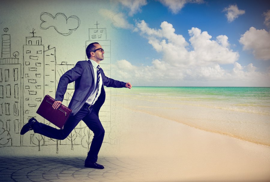 Man in businss suit leaping from work into beach