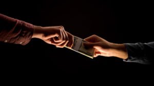 Hand giving cash to another hand