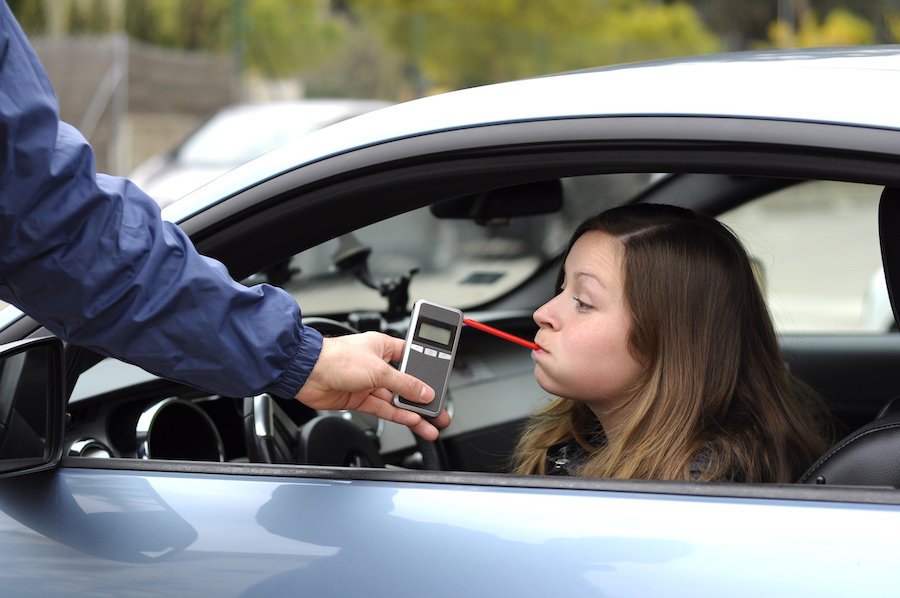 Police administering preliminary breath test to DUI suspect in car