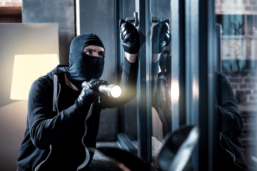 Masked man burgling a house - robbery is distinguished from burglary by the use of force or fear