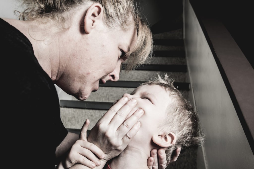 Madre enojada sosteniendo el rostro del niño