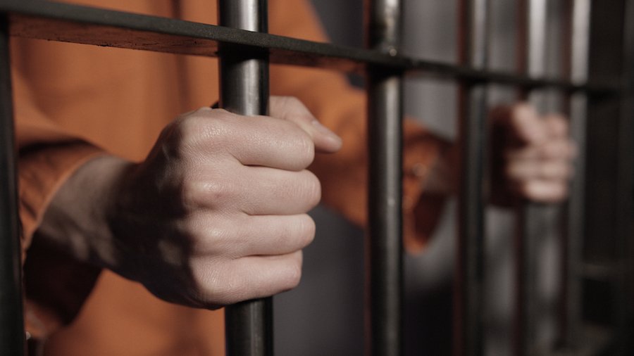 Prisoner's hand griping the bars of a jail cell