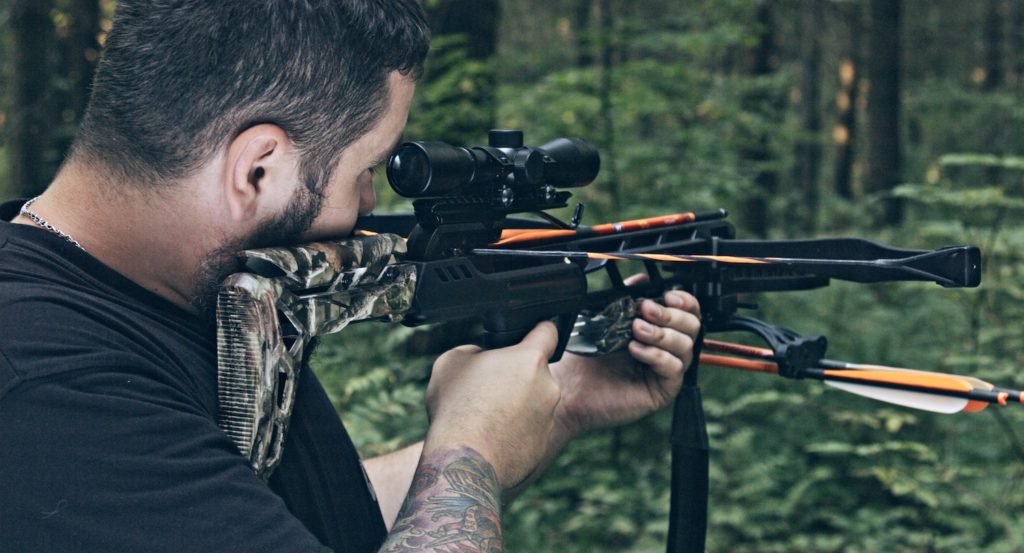 Man aiming crossbow in forest