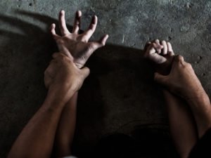 Manos sosteniendo otra par de manos hacia abajo durante la violación de NRS 200.366