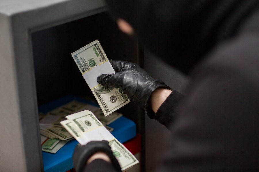 Hombre robando dinero de una caja fuerte