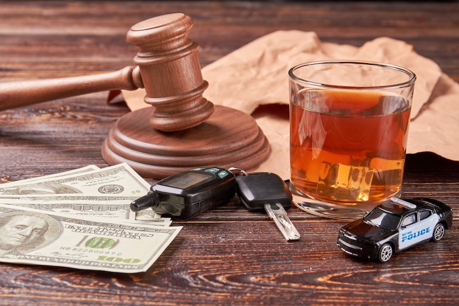 gavel, cash, car keyes, police car toy, and tumbler of beer