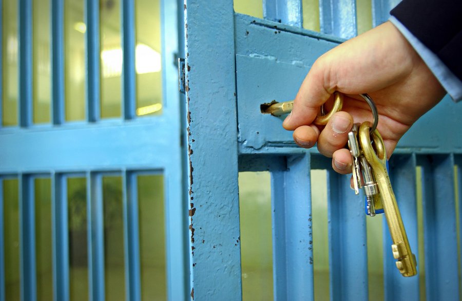 Police officers unlocks the door in prison corridor to let inmate out on bail