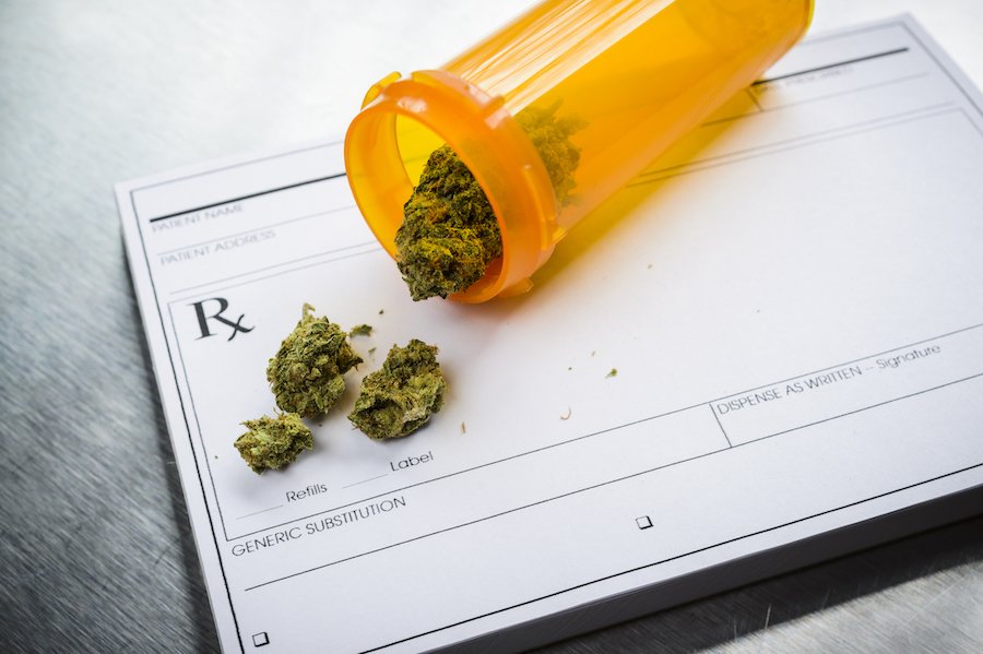 Prescription bottle holding marijuana over RX form