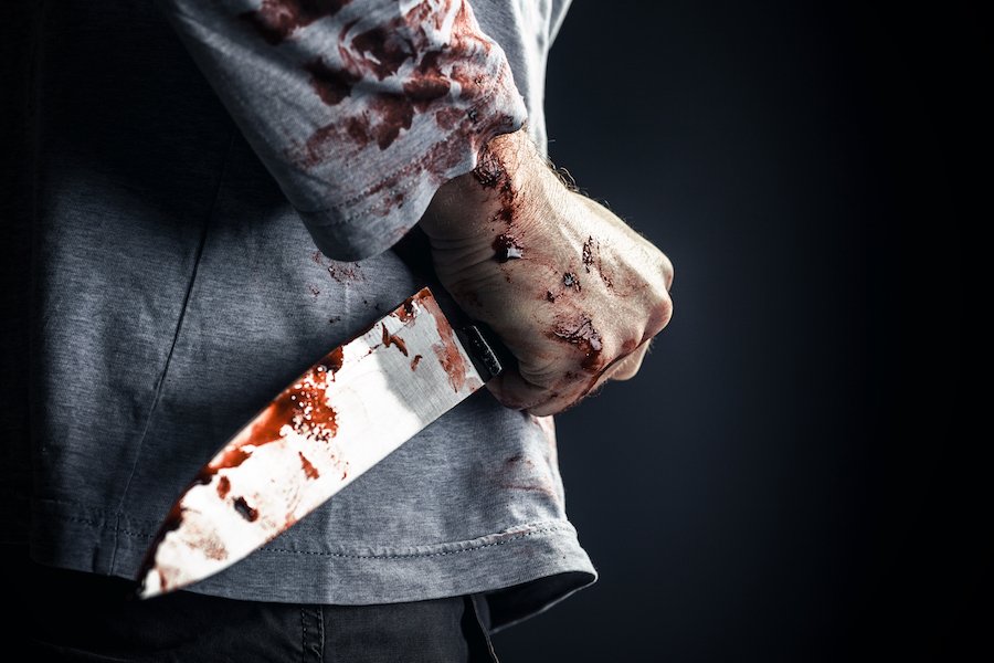 Asesino sosteniendo un cuchillo ensangrentado