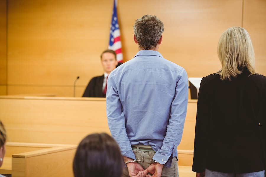 Hombre con esposas apareciendo con abogado ante un juez