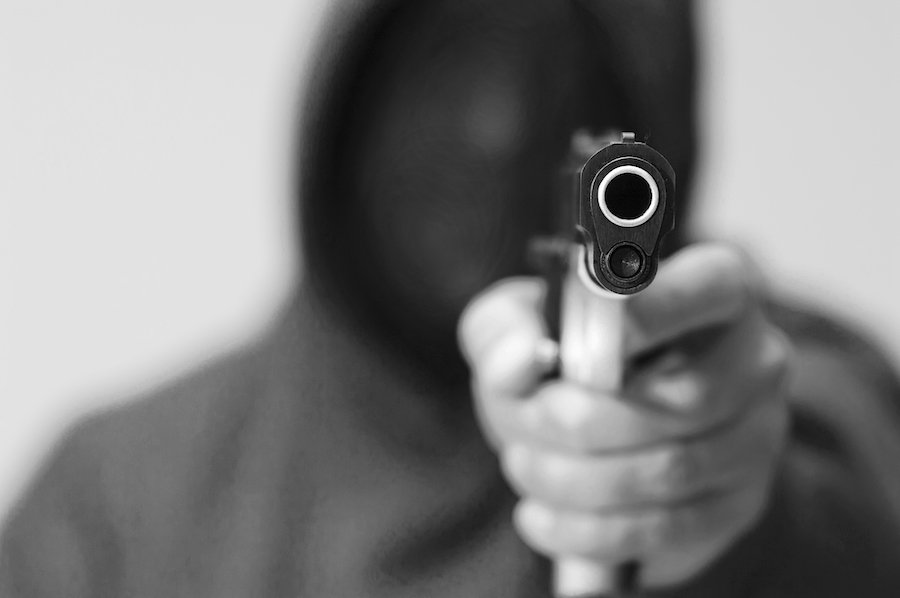 Hombre con capucha sosteniendo un arma, quien enfrentará una sentencia más severa bajo ARS 13-706.