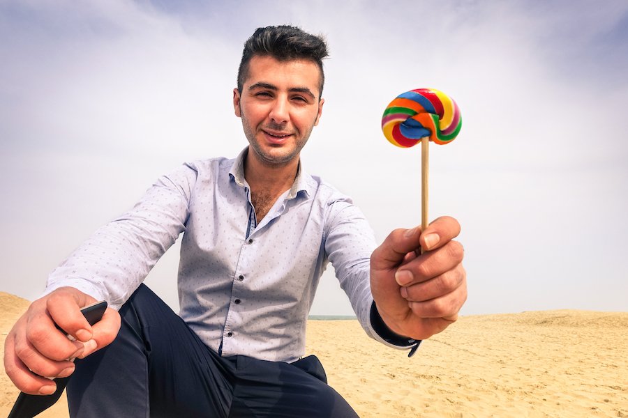 Hombre sosteniendo una paleta para ofrecerla a un niño detrás de la cámara para ilustrar la solicitud de un menor