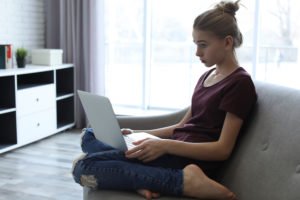 Young teen girl on computer looking distraught