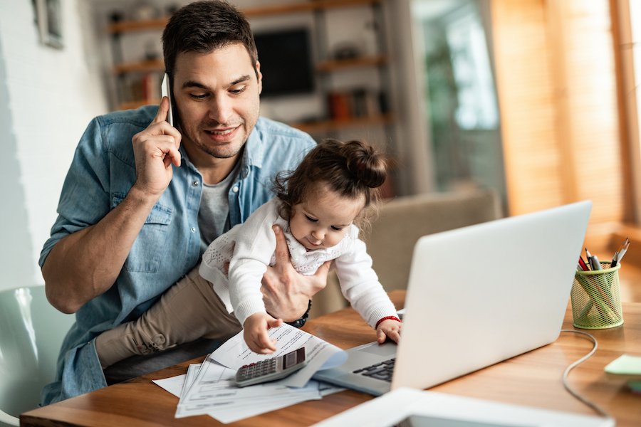Dad holding baby while working at home from desk