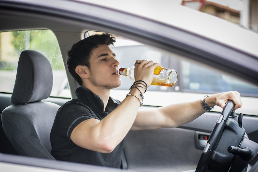 Conductor detrás del volante mientras bebe cerveza
