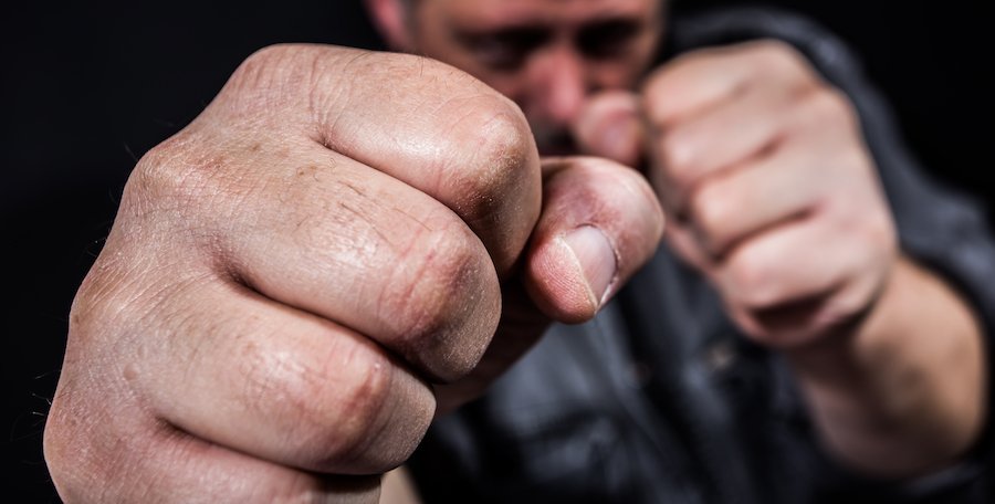 Hombre cometiendo agresión con puños levantados y tratando de golpear