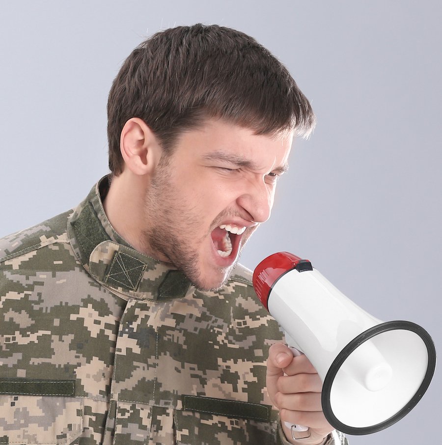 Hombre en fatigas gritando en megáfono