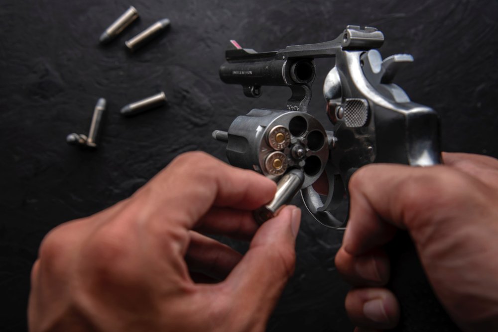man placing bullets into a revolver - unlawful possession of ammunition by a convicted felon is a crime in California