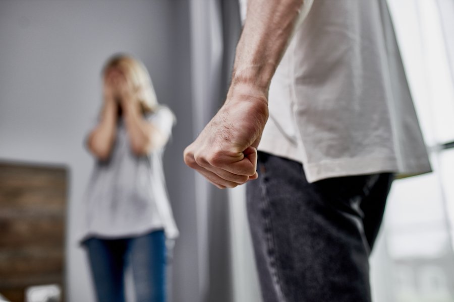 Hombre sosteniendo puño cerca de mujer con aspecto angustiado