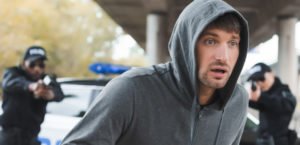 Hooded man being chased by police with guns